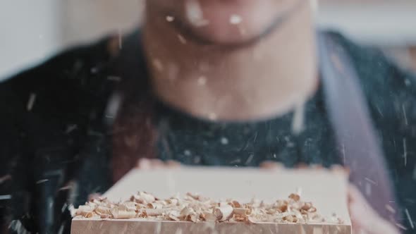 Carpentry Works  Worker Blows Off the Wood Shavings From a Detail alt