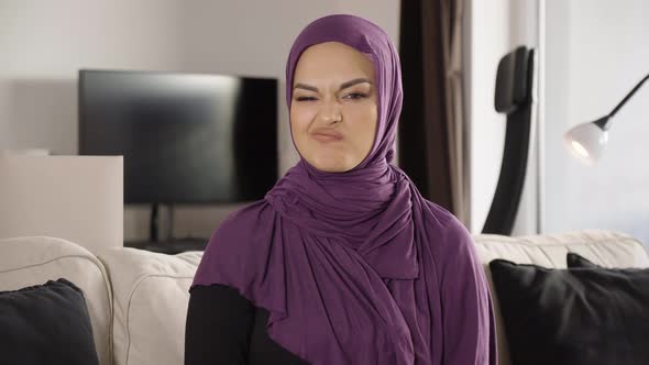 A Young Beautiful Muslim Woman Shakes Her Head at the Camera and Shows a Thumb Down alt