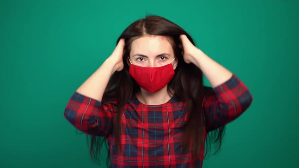 Young Girl in a Red Medical Mask Straightens Her Hair