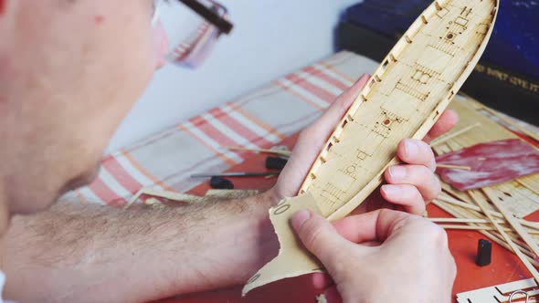 Hands of Man Adjusts Plywood Details for Ship Model Grinding on Sandpaper