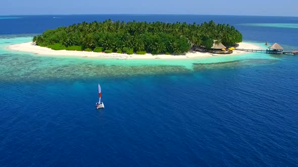 Aerial drone view of a man and woman sailing on a boat to a tropical island. alt