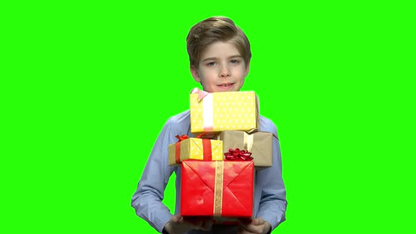 Portrait of Little Boy Holding Lots of Gift Boxes in His Two Arms alt