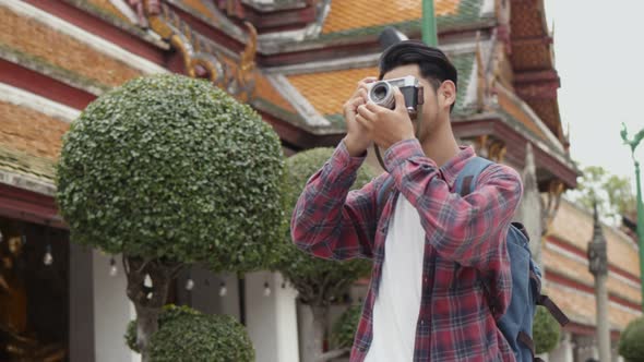 Attractive young Asian man tourists traveling and taking a photo in temple Thailand.