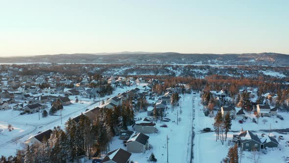Winter aerial over homes in a picturesque, snow covered community on a cold winter day. alt