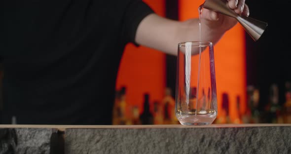 Bartender Pours Portion of Alcohol From Jigger to the Cocktail Glass in Slow Motion Making the alt