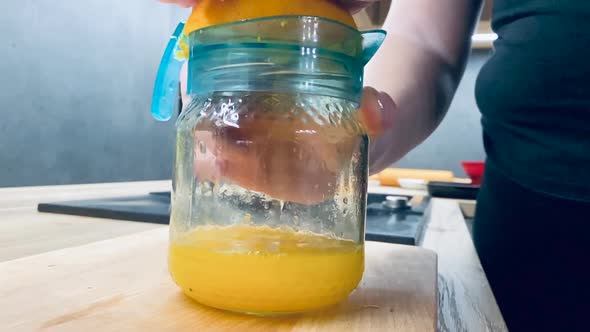 Juicing fresh orange for healthy juice on kitchen counter from side shot in slow motion alt