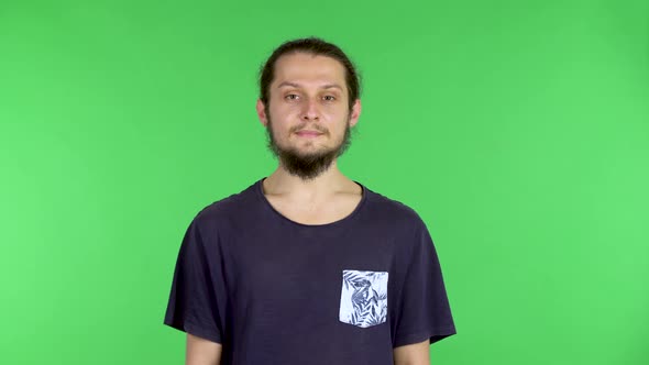 Young Man in Green Room and Looks at the Camera, Chroma Key Background, a Man Smiles, Positive alt