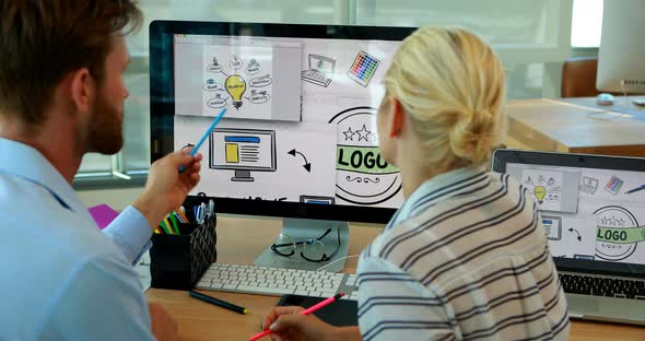 Graphic designers working over computer at desk alt