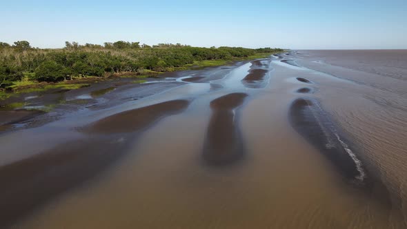 Aerial shot of waves, sand banks and green nature by Rio de la Plata alt