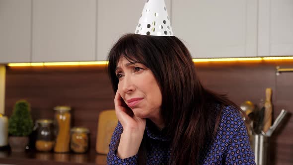 Close Up Upset Aged Woman in Party Hat Celebration Holiday Birthday Alone Home alt