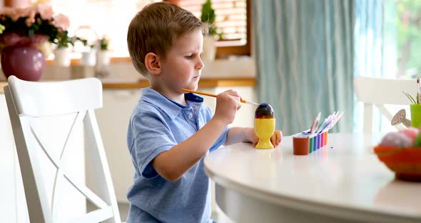 Cute Little Boy Painting Easter Eggs at Home