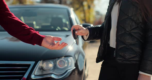 Man Gets the Car Key From Seller  Satisfied  Trade Closed  New Car in the Background alt