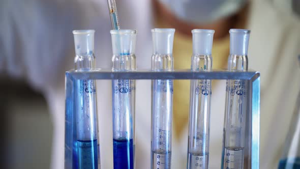Scientist in Laboratory Doing Chemical Experiment with Blue Liquid in Test Tubes alt
