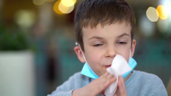 Portrait of Masked Boy Wiping His Mouth with Napkin in Restaurant alt