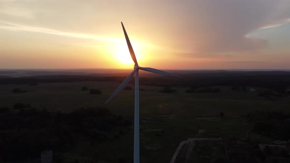 Silhouette of a Wind Turbine  Against the Background of an Orange Sunset alt