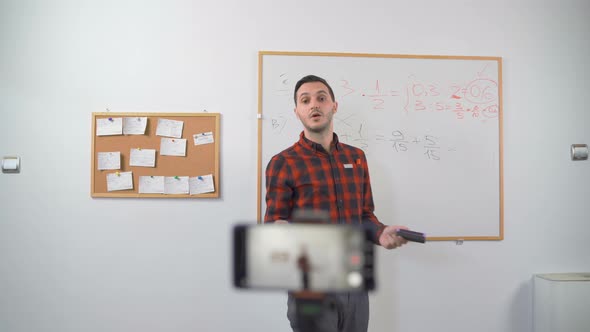 Young Teacher Teaching Remotely Using Smartphone Camera To Stream Lesson alt