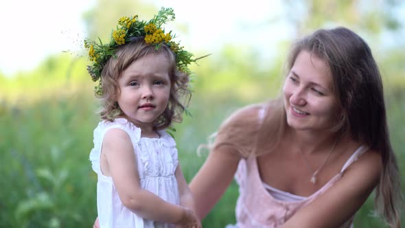 Happy Mother and Daughter with the Flower Wreath