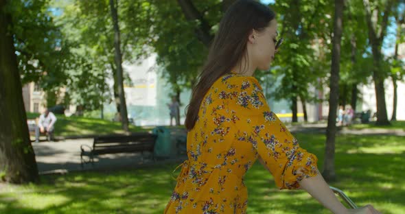 Cyclist Woman In Park In Dress. Sport And Recreation. Cycling Woman In City Park On Bicycle. alt