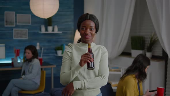Happy Woman with Dark Skin Drinking Beer Having Fun During Holiday Party alt