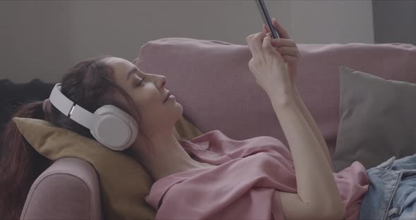 Young Woman Listening To Music On Headphones And Using Smartphone