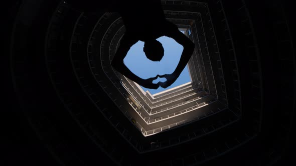 Modern Round Building with Blue Sky on Top. Silhouette of a Man Who Shoots Video on a Phone or