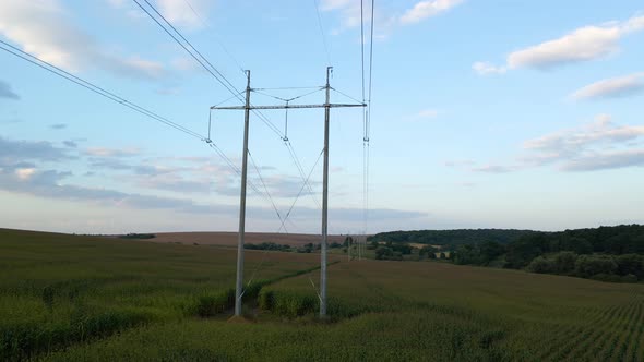 High Voltage Tower with Electric Power Lines Between Green Agricultural Fields alt