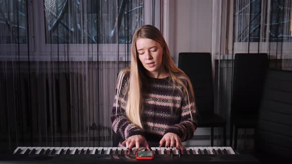 A Young Girl with Long White Hair Plays the Piano and Sings a Song alt