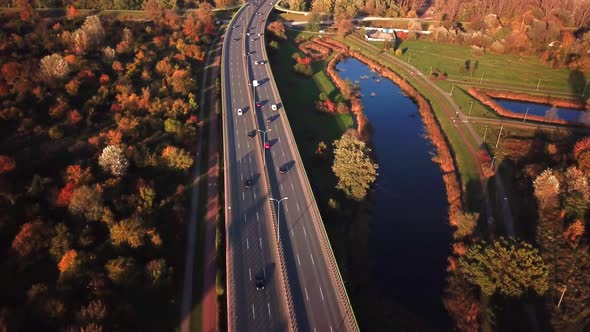 4K AERIAL: Cars and semi truck driving on busy highway across the country in beautiful autumn evenin alt