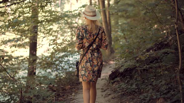 Girl In Dress Walking In Greenwood. Carefree Female Exploring Green Forest In Sunny Time. alt