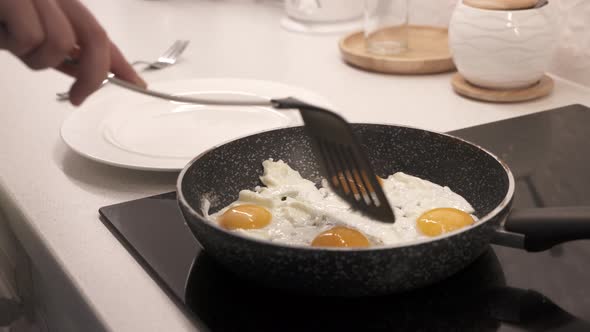Woman Cooking Scrambled Eggs on Electric Stove Top in the Kitchen Frying Pan with Fried Eggs on alt