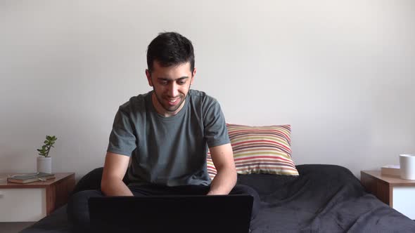 Young man working from his laptop on his bed. Concept of telework and home-office. alt