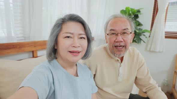 Asian beautiful old woman and senior man couple in love use mobile phone for video call with family. alt