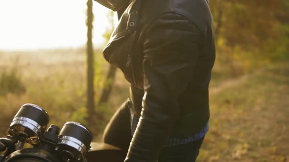 Back View of a Man in Helmet and Leather Jacket Coming Up to His Bike and Starting the Engine While alt