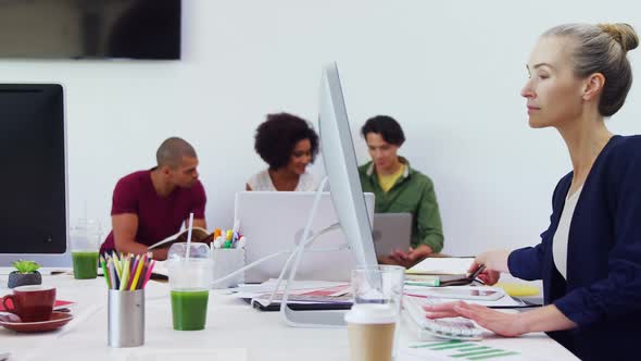 Woman working on desktop pc with colleagues in background 4k alt