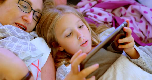 Mother and daughter using digital tablet in tent 4k alt