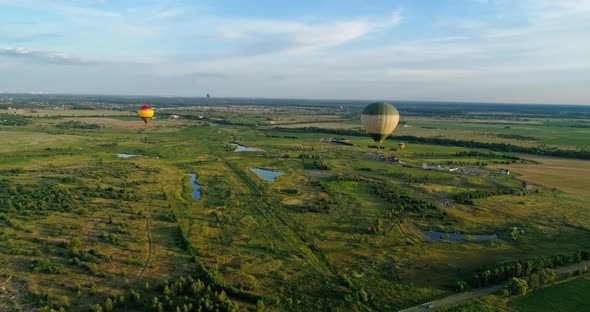 Colorful aerostats among nature. Hot air balloons fly in the sky over fields and lakes in the countr alt