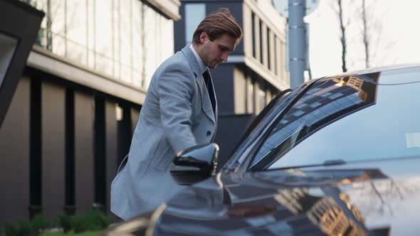 Young Businessman Walks to a Black Car and Sits in the Passenger Seat an Elegant Man in a Suit alt