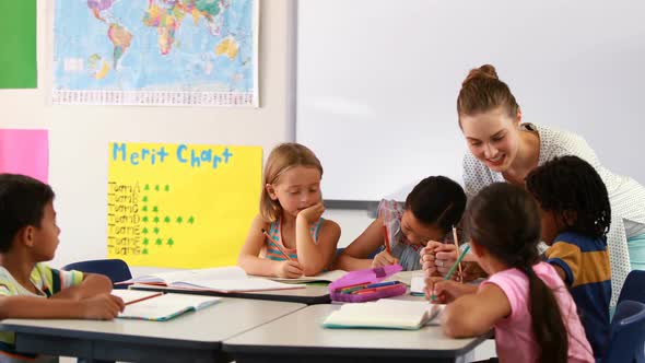 Teacher helping kids with their homework in classroom alt