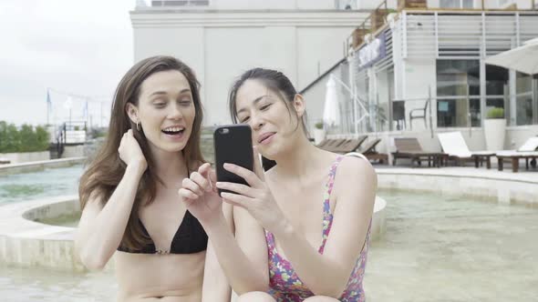 Women laughing at multimeda smartphone while relaxing at spa