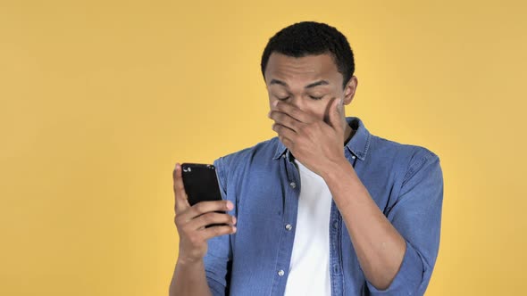 Young African Man in Shock While Using Smartphone alt
