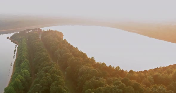 An Aerial View of the Forest Lake in a Foggy Morning Mist During the Morning Sunrise alt