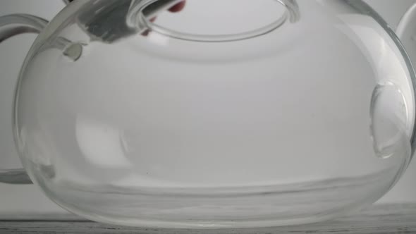 The Hand of an Unidentified Man Pours Fragrant Tea Into a Glass Teapot alt