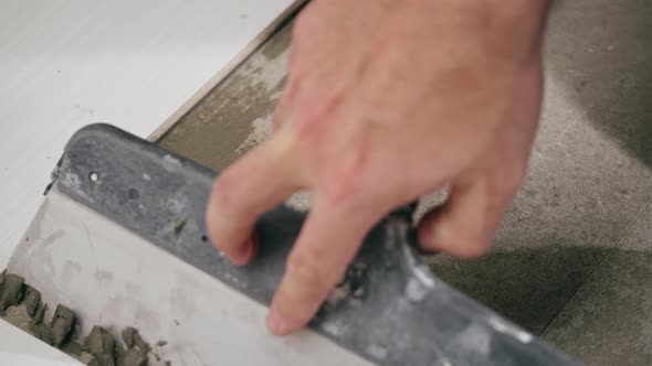 Builder Laying Tiles Using Cement and Spatula Closeup Man Installing Ceramic Slabs on Floor and alt