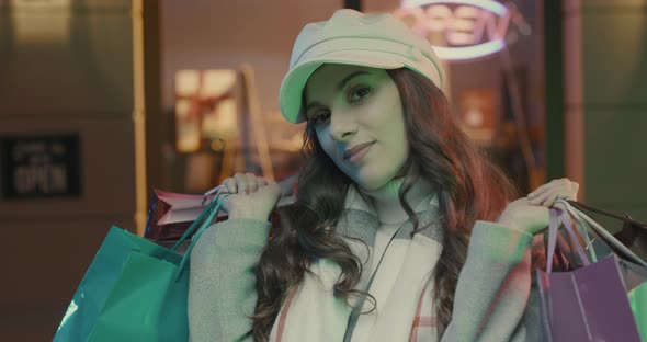 Young woman walking in the city streets and carrying shopping bags, she is happy and smiling