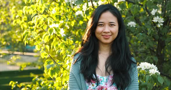 Portrait of Cute Asian Girl in Park with Green Trees