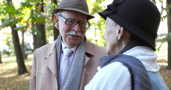 Portrait of Happy Retired Family Couple Talking Emotionally During Walk in Park alt