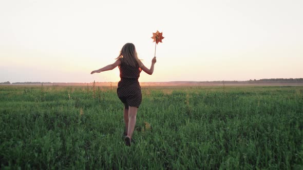 Girl Child Running with a Windmill in a Field alt