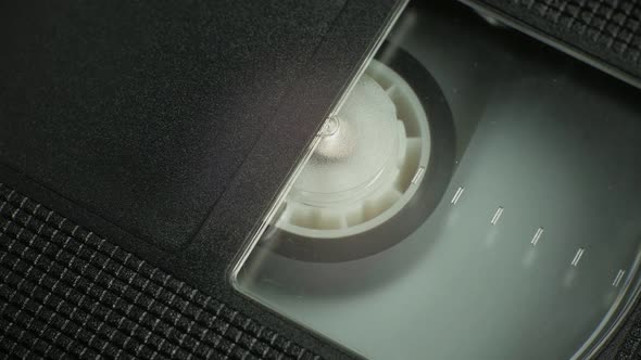 The Right Side of the VHS Cartridge at an Angle. a Film Reel Spins in a Small Cassette Window alt