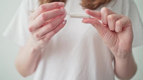A Tampon in Women's Hands on a White Background