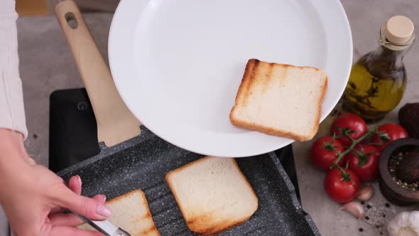 Woman Putting Toasted Bread From Grill Frying Pan Onto White Ceramic Plate alt